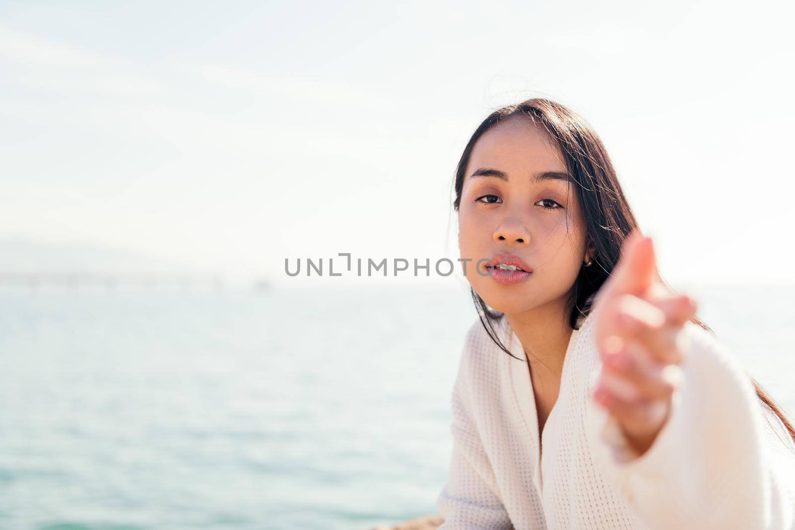 young asian woman dressed in white reaching out her hand to the camera, concept of beauty and purity