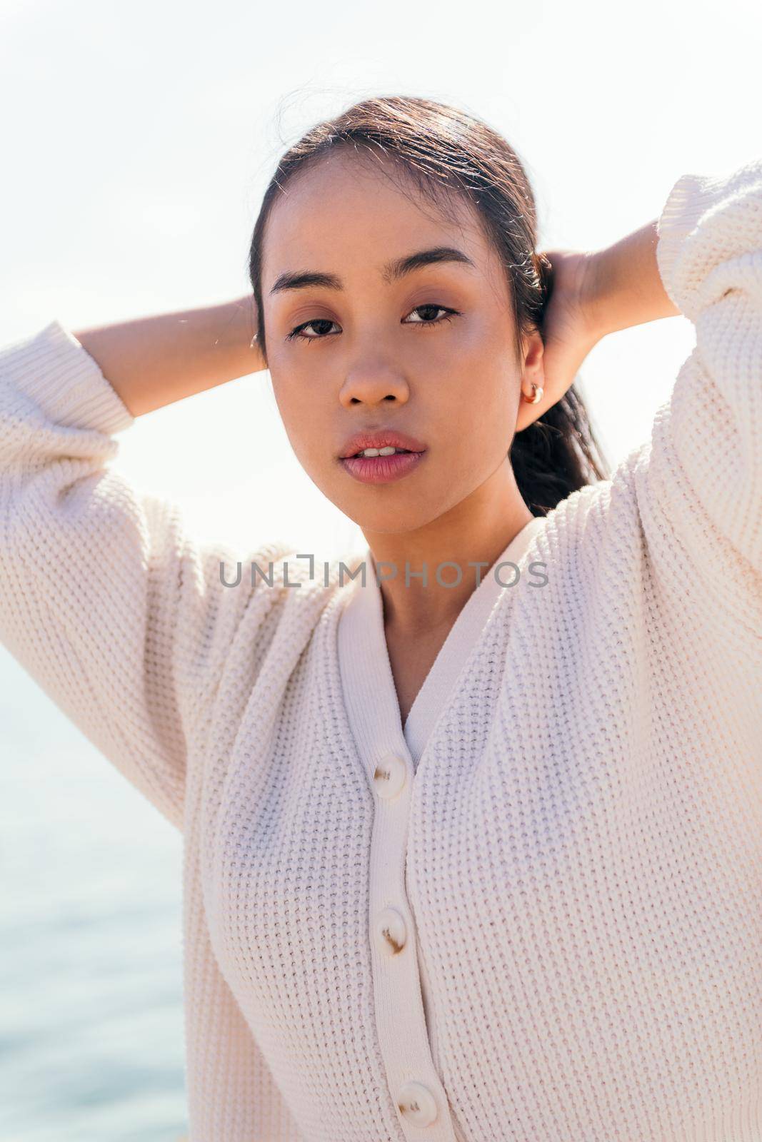 sensual young asian woman in white holding up her hair with her hands, concept of beauty and purity