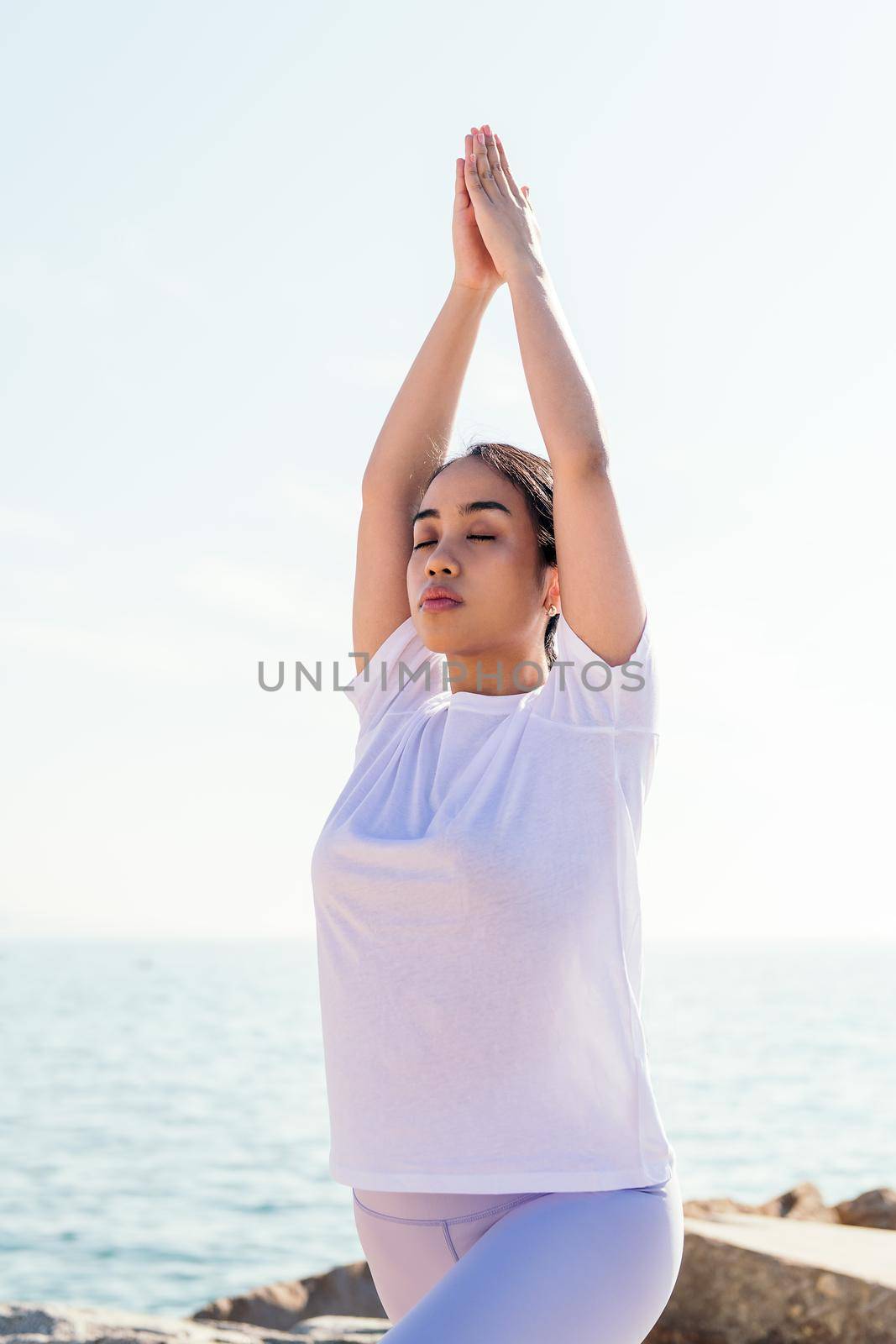 young asian woman meditating practicing yoga with her eyes closed, concept of spirituality and relax