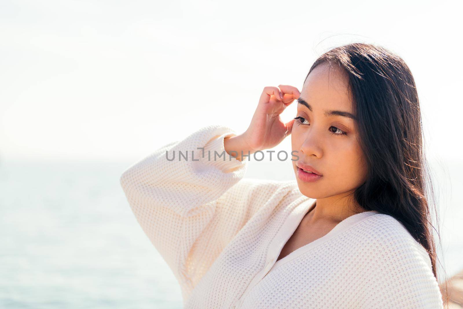 young asian woman in white touching her hair outdoors, concept of beauty and purity