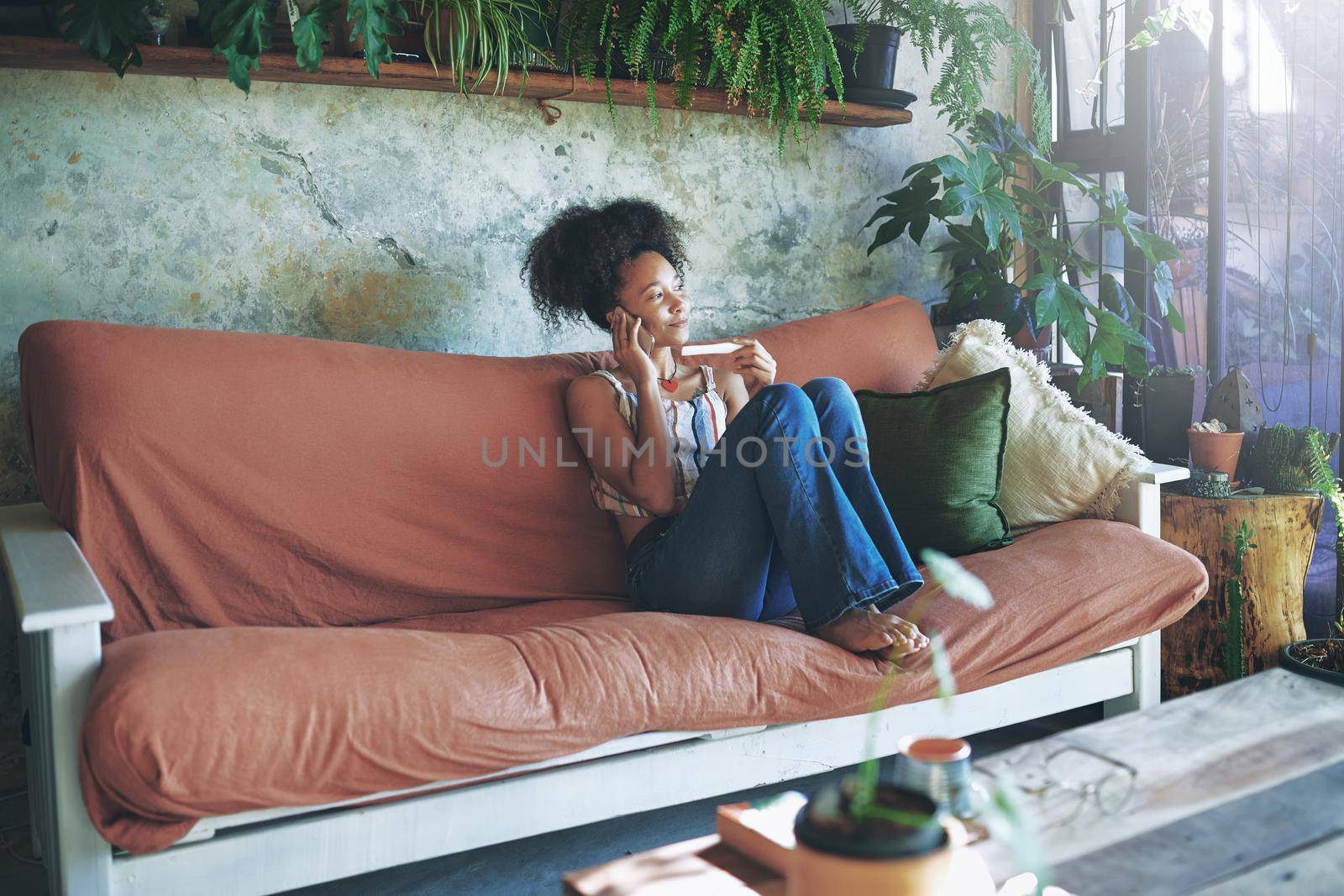 Shot of a young woman taking a pregnancy test on her sofa while talking on her smartphone