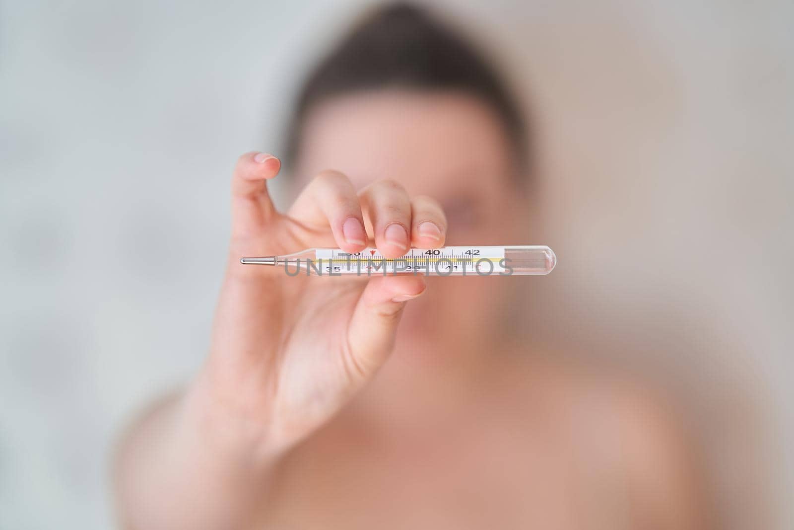 Girl holds a thermometer. High body temperature on a thermometer. Close-up.