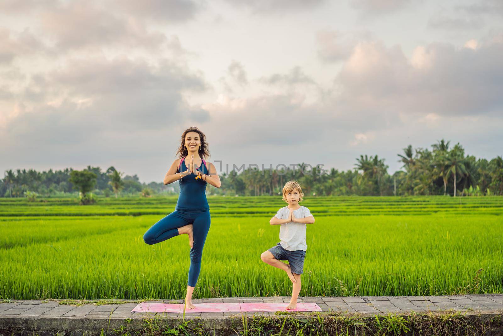 Boy and his yoga teacher doing yoga in a rice field.