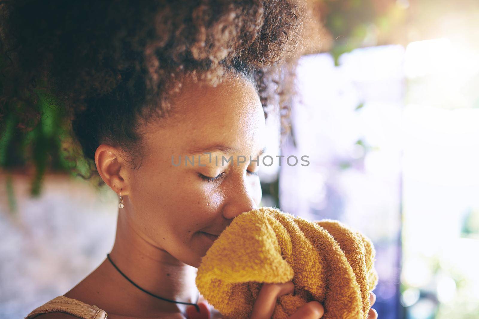 Shot of a beautiful African woman smelling freshly washed laundry while at home - Stock Photo