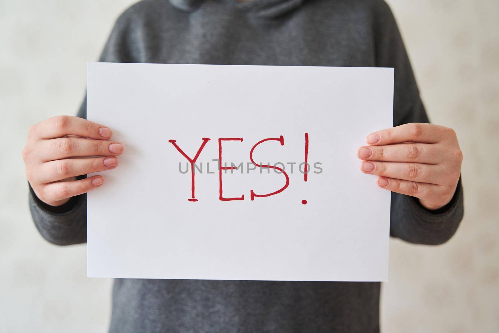 Girl holds a sheet of paper with the inscription YES. The inscription YES in the girl's hands on a white sheet