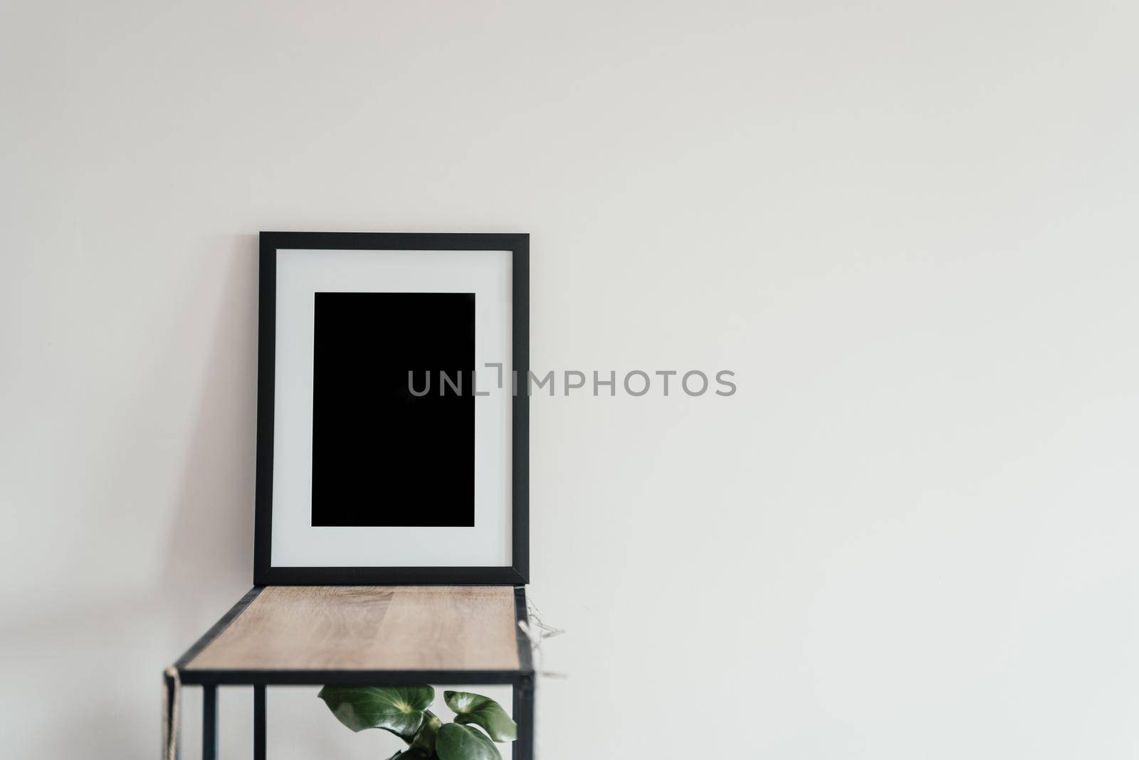 Blank wooden photo frame stands in the interior on a white background. Mockup poster frame close up in home interior.