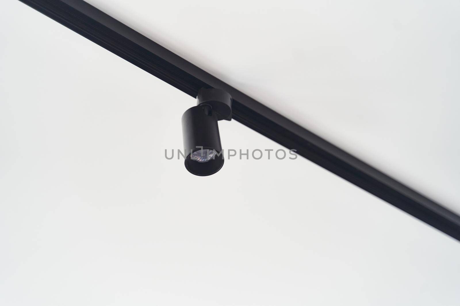 Modern LED black track spot lights in the interior. Hanging lamps spotlights attached to a concrete ceiling in an office loft room