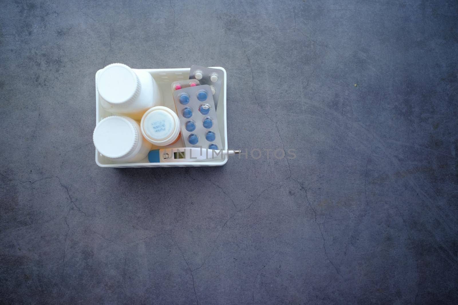 medical pill container, blister pack and thermometer in a plastic organizer .