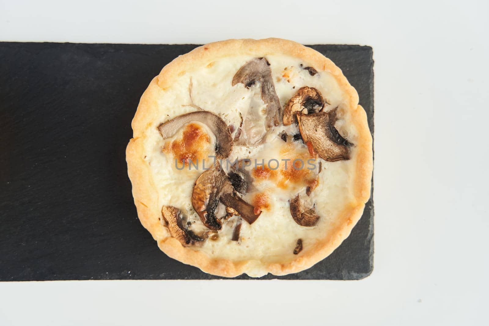 Tart with mushrooms and cheese on a white plate. Close-up