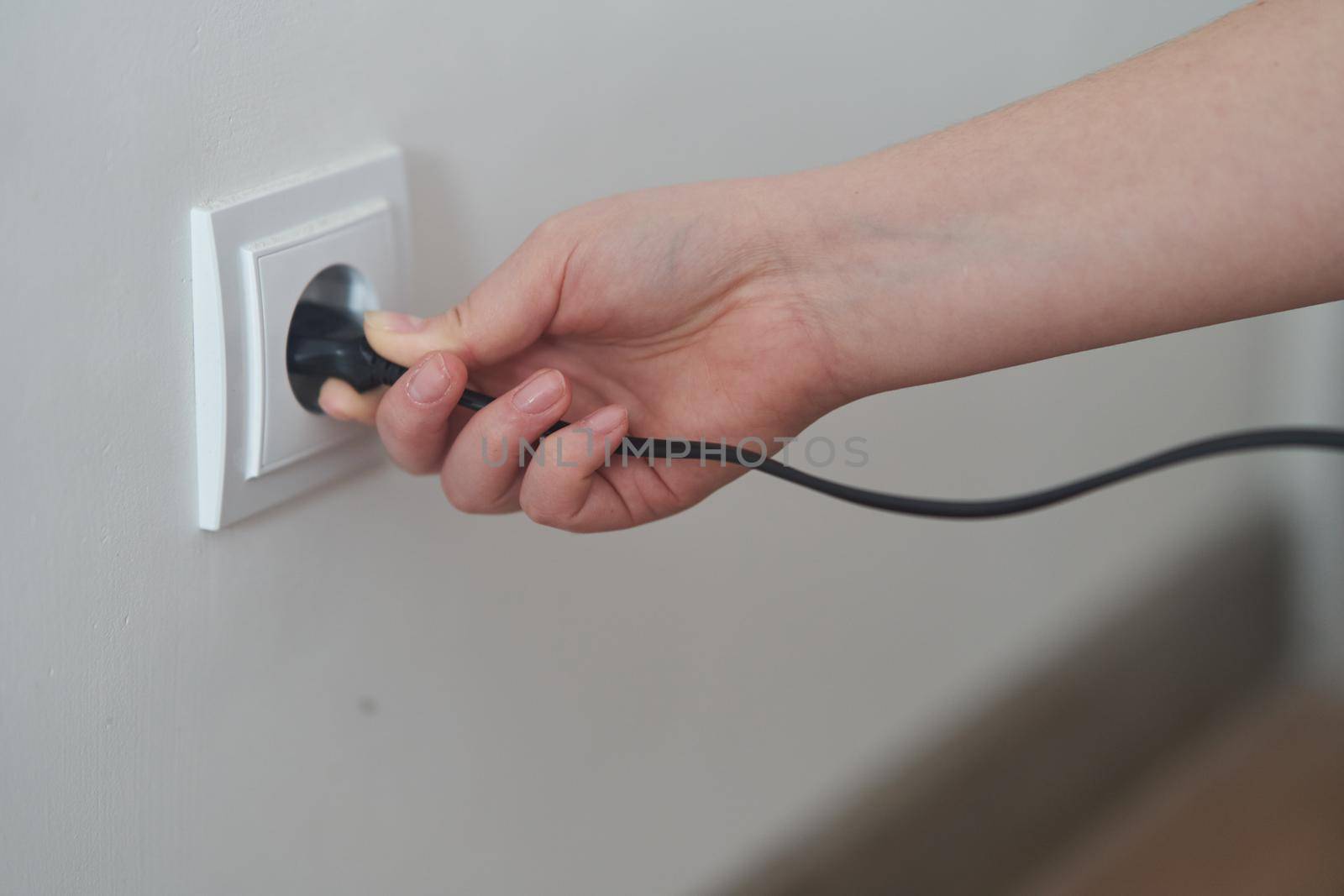 A young girl inserts a plug into an outlet. Young woman plugs the phone charger into the socket. High quality photo