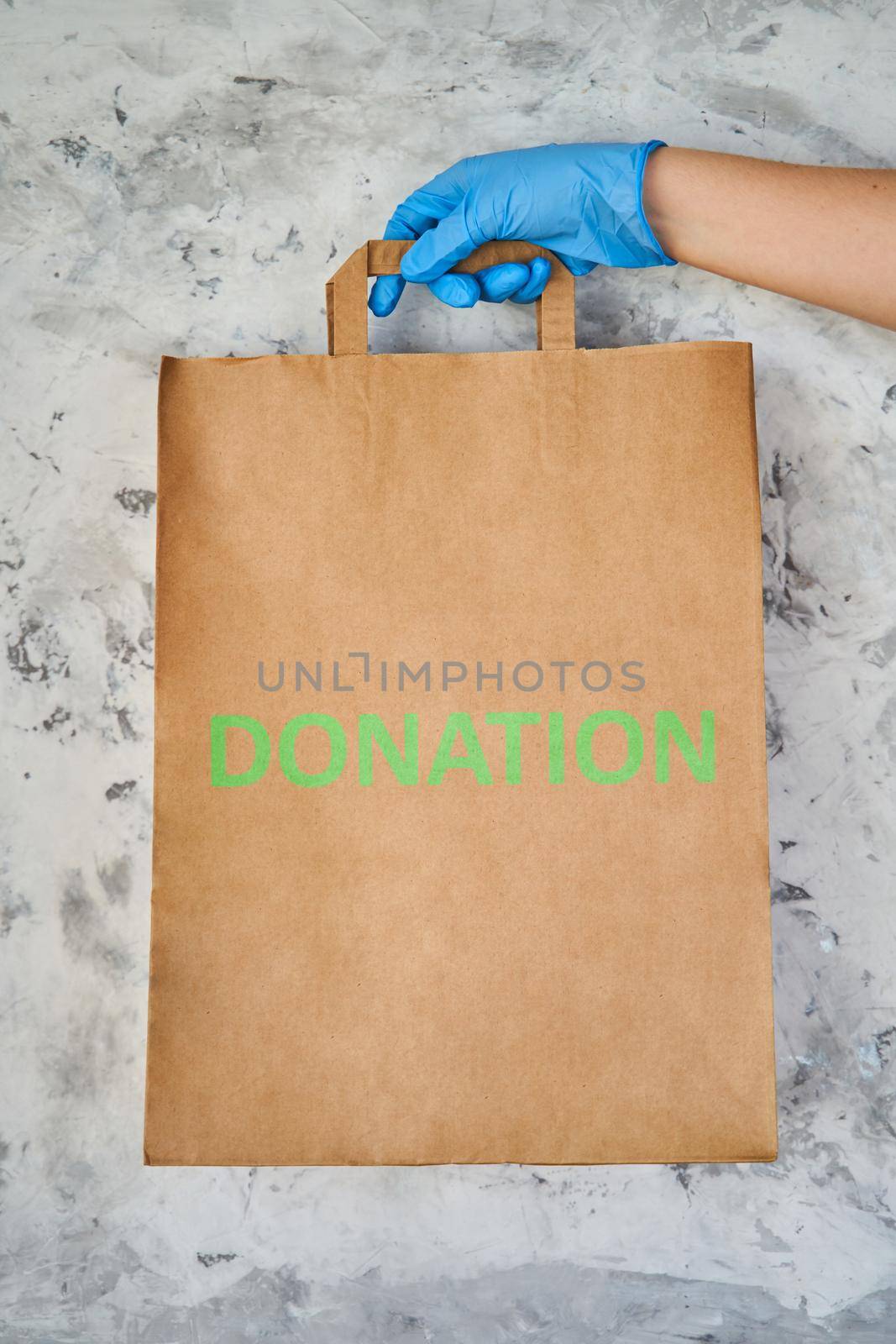 Food donation box. Woman delivering food in paper bag during Covid 19 outbreak. Girl holds a paper bag in blue gloves. Coronavirus Prevention.