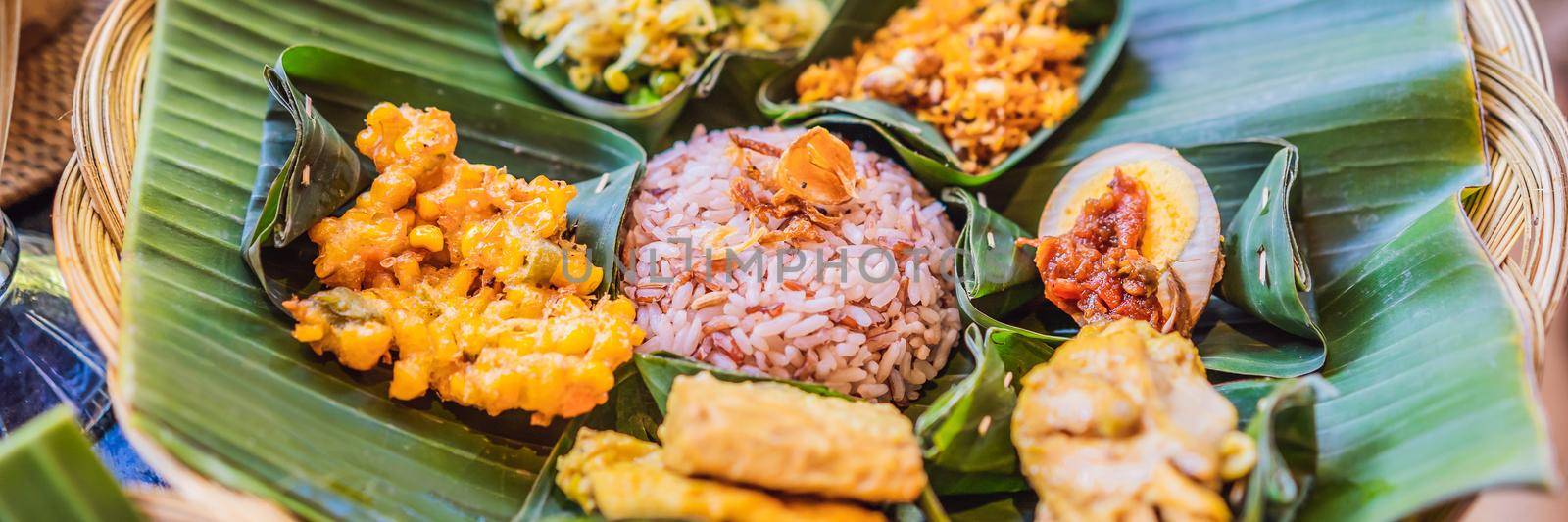 Nasi lemak, Nasi campur, Indonesian Balinese rice with potato fritter, sate lilit, fried tofu, spicy boiled eggs, and peanut. BANNER, LONG FORMAT