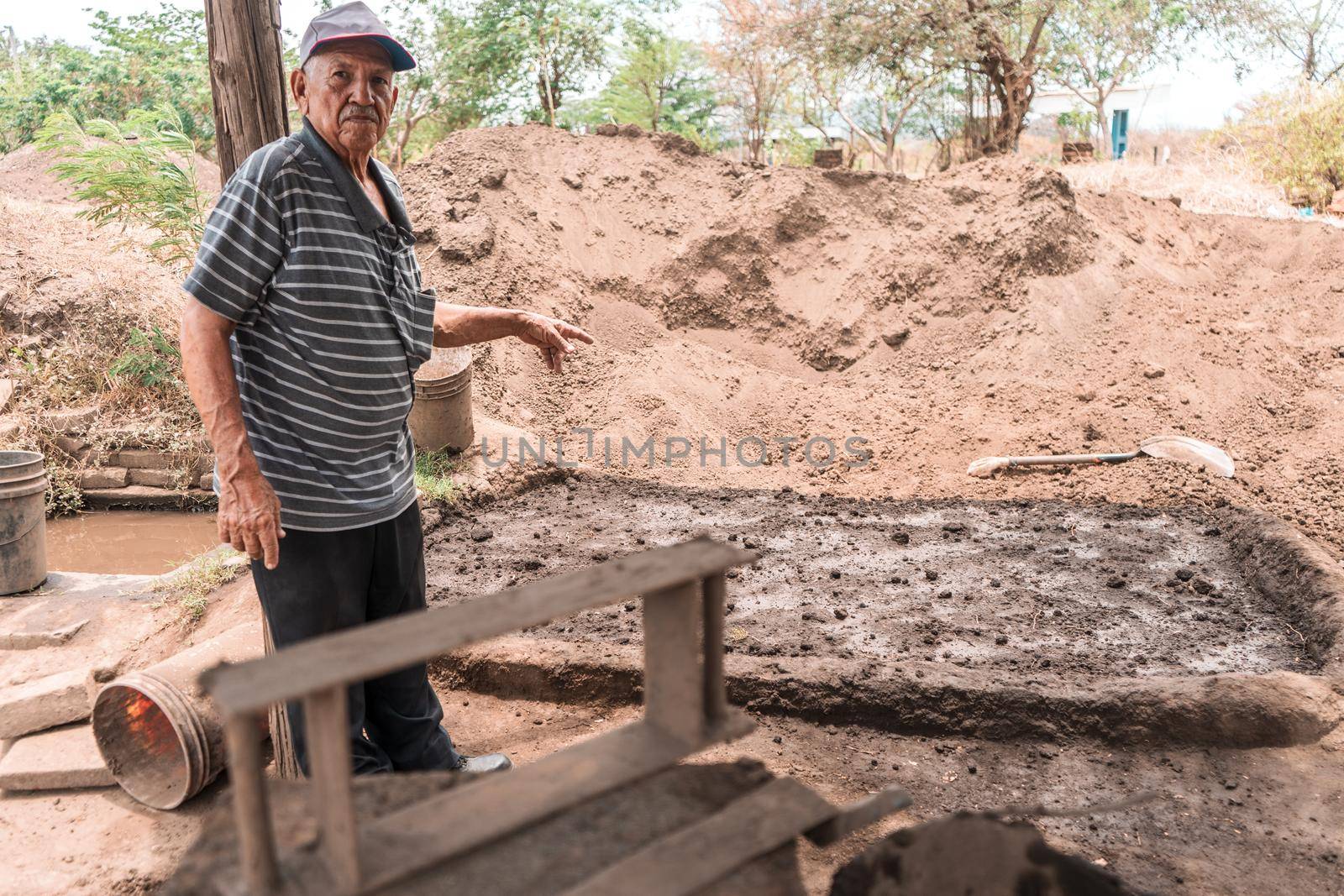 Owner of a mud brick construction workshop in front aa pile where pieces are made by cfalvarez
