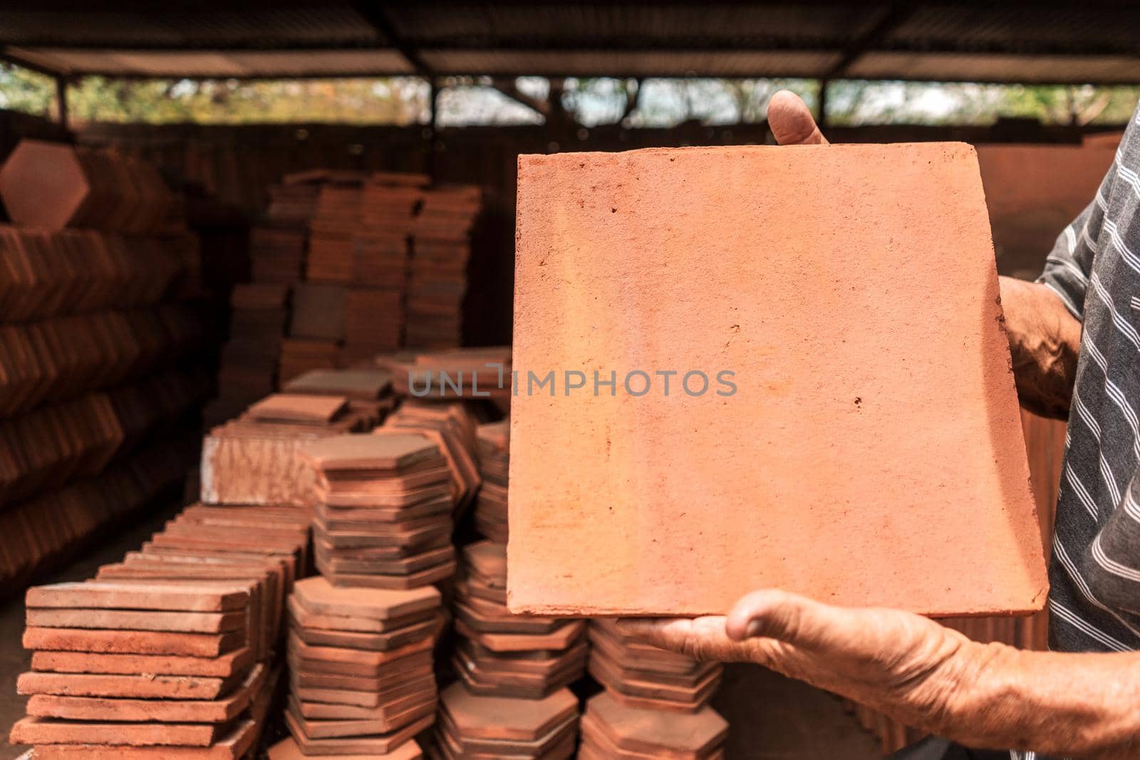 Old man holding a mud brick in his hands made in a craft workshop in La Paz Centro Nicaragua