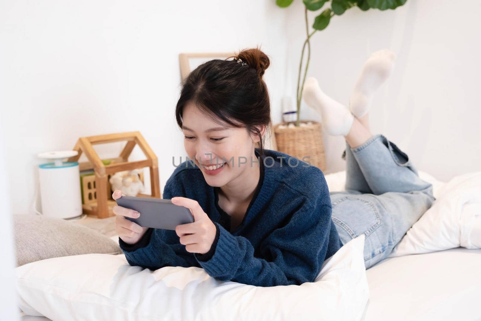 Beautiful woman using a smart phone in the morning on the bed at home.