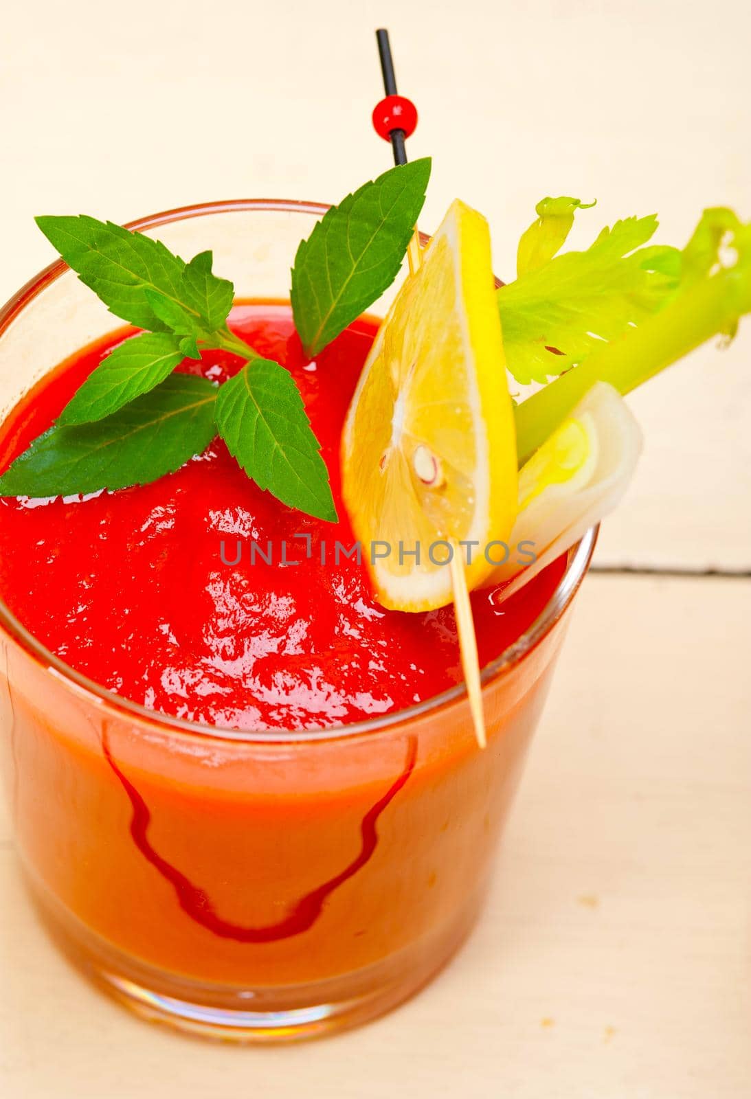 fresh tomato juice gazpacho soup on a glass over white wood table