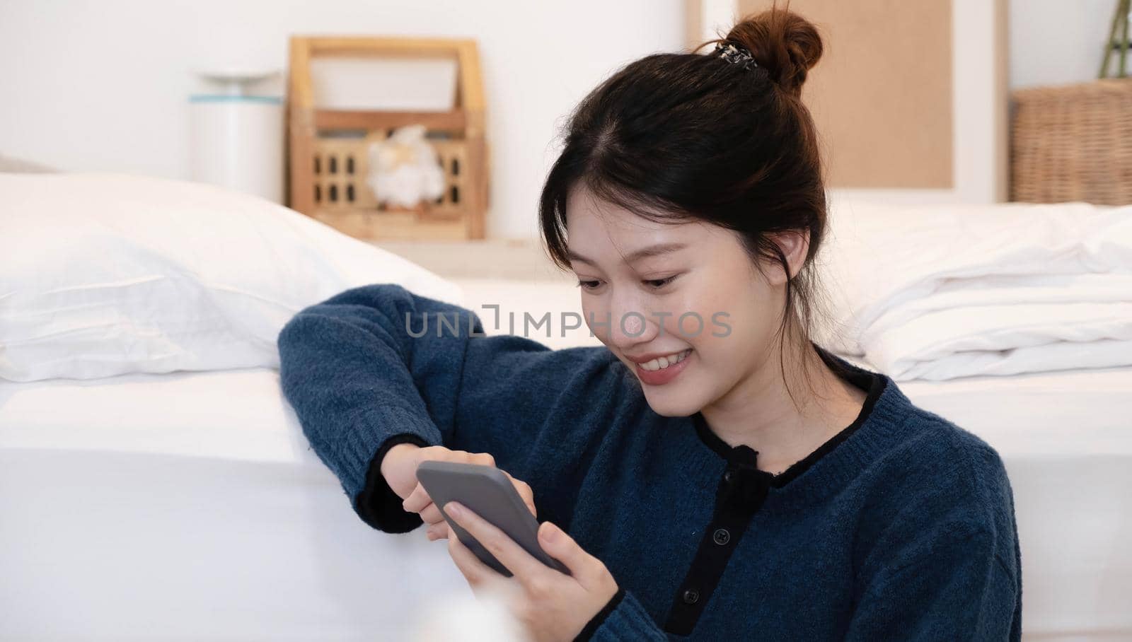 Beautiful woman using a smart phone in the morning on the bed at home.