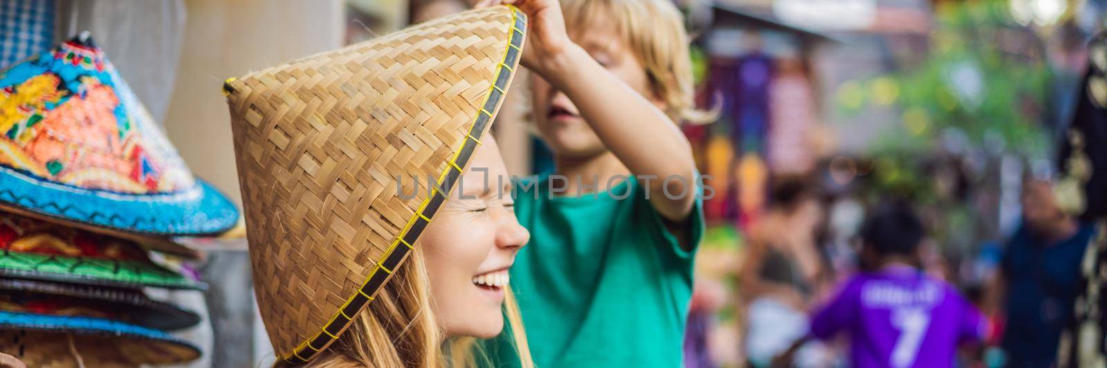 Mom and son travelers choose souvenirs in the market at Ubud in Bali, Indonesia. BANNER, LONG FORMAT