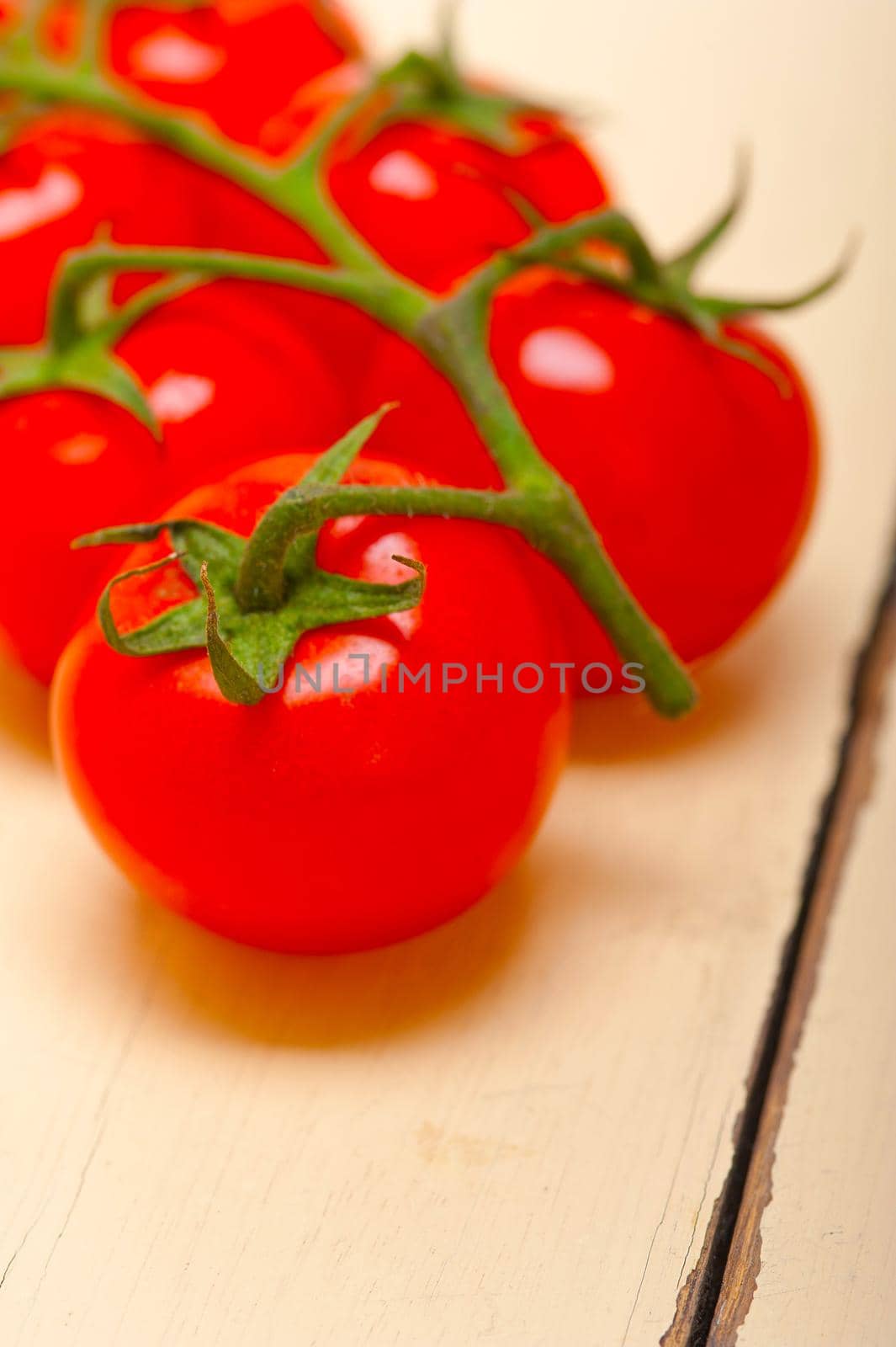 fresh cherry tomatoes on a cluster over rustic wood table