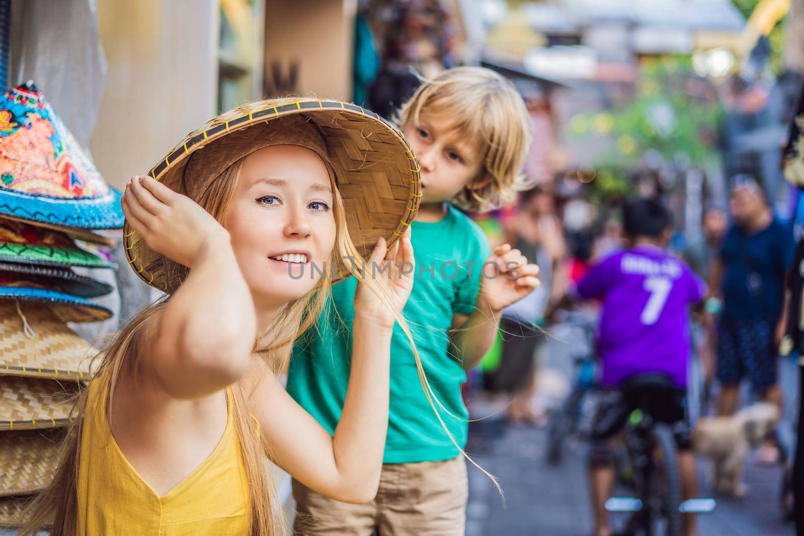 Mom and son travelers choose souvenirs in the market at Ubud in Bali, Indonesia.