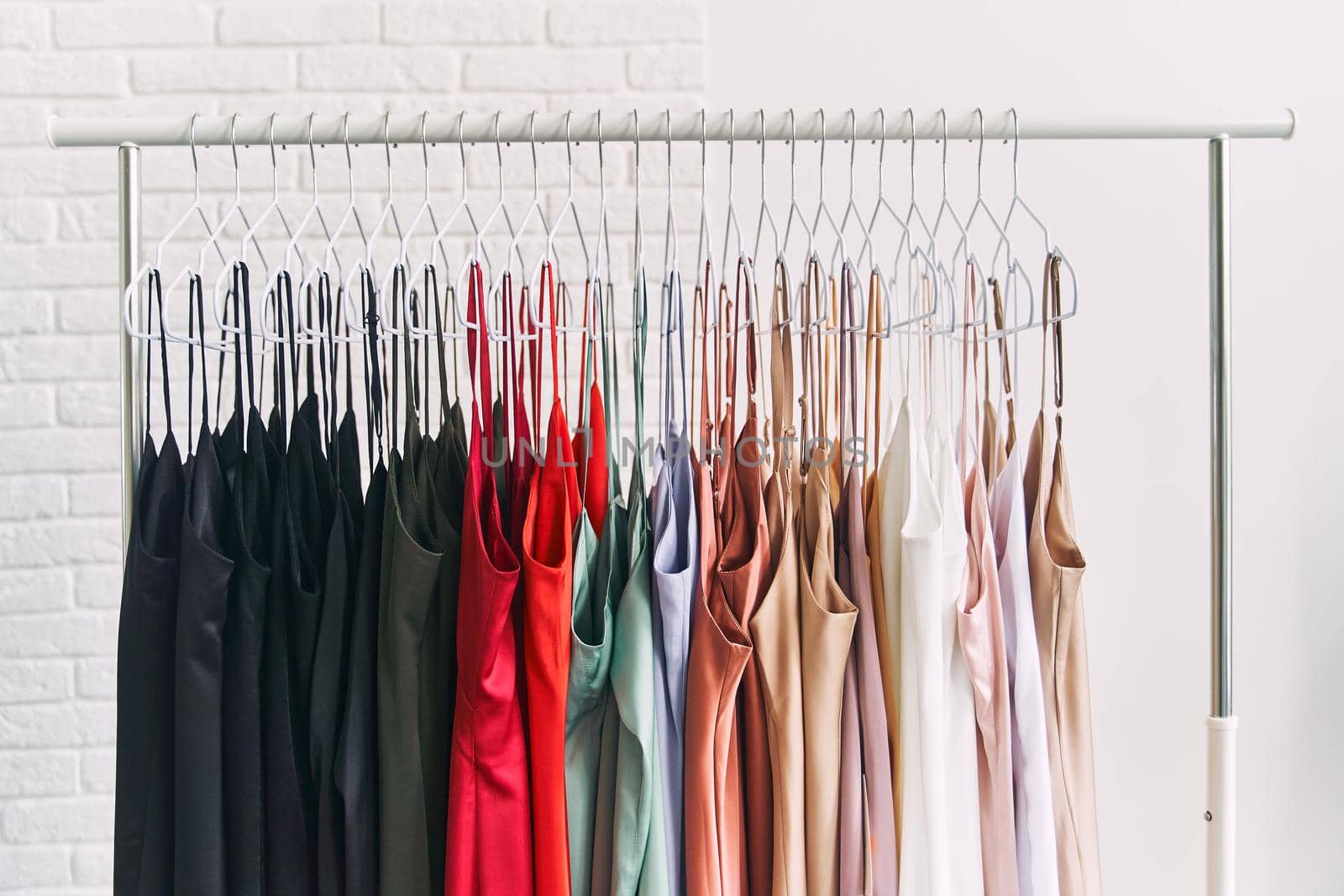 Multi-colored dresses hang on hangers in the store. Sale of women's dresses. Variety of different female colorful clothing hanging.