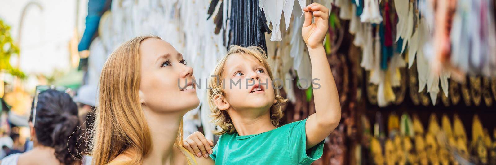 Mom and son travelers choose souvenirs in the market at Ubud in Bali, Indonesia BANNER, LONG FORMAT by galitskaya
