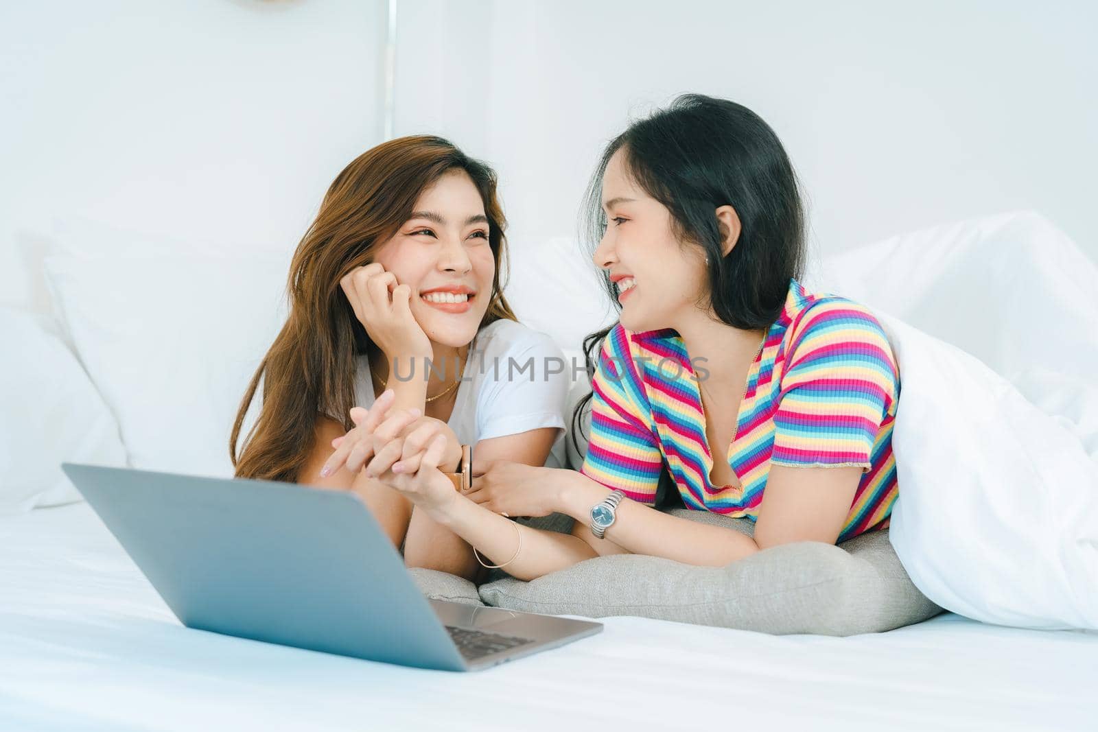 lgbtq, lgbt concept, homosexuality, portrait of two asian women posing happy together and loving each other while playing computer laptop on bed by Manastrong