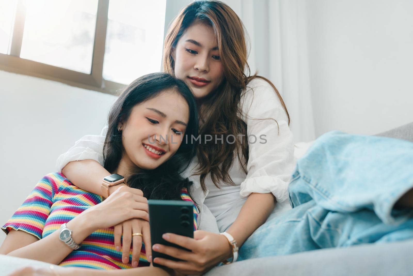 lgbtq, lgbt concept, homosexuality, portrait of two asian women enjoying together and showing love for each other while using smartphone mobile to take selfies by Manastrong