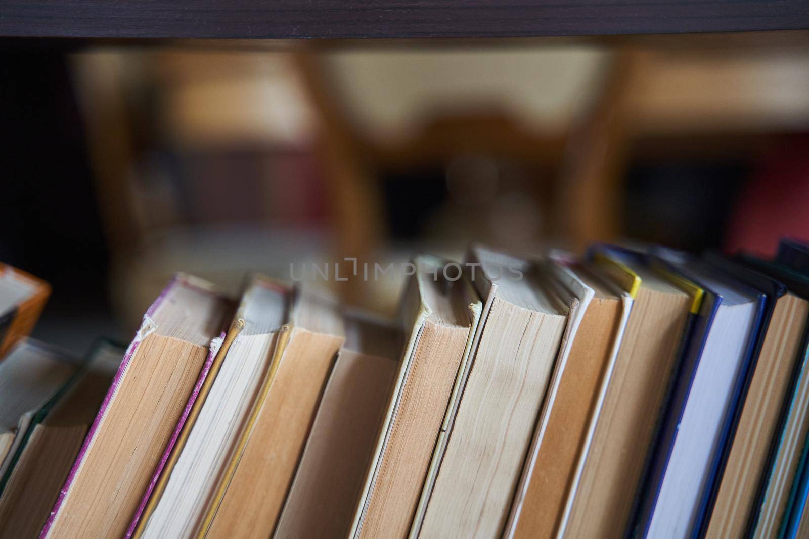 Piles of books on a wooden bookshelf. Home library