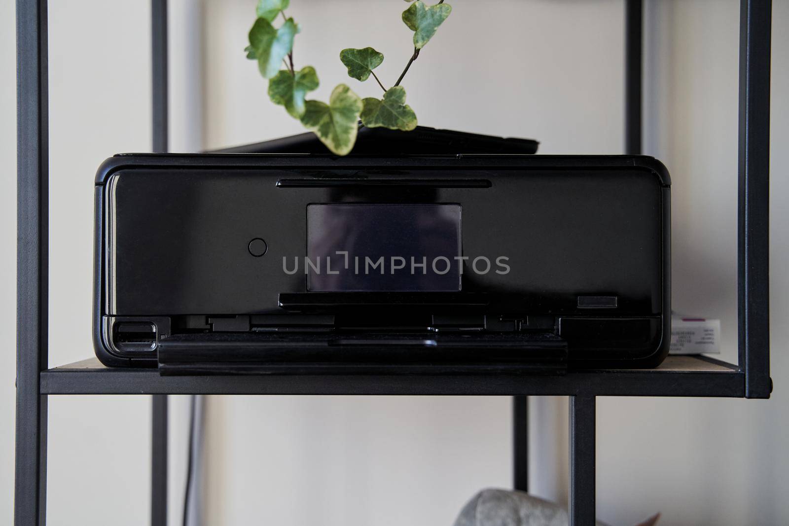 Black inkjet printer is on the shelf . High quality photo