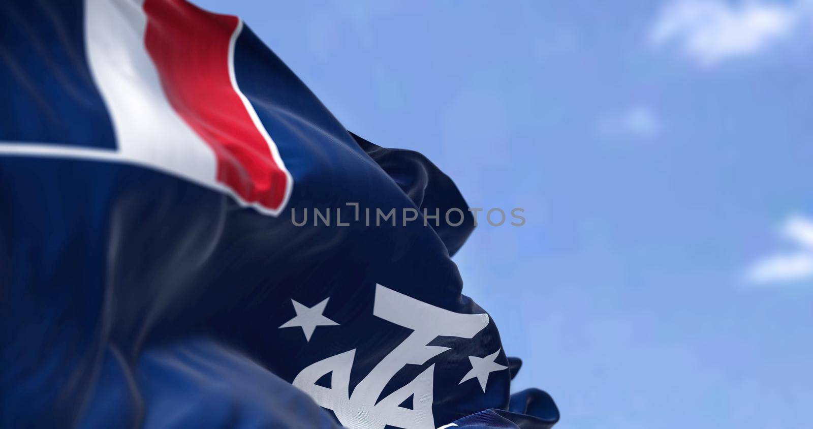 The flag of the French Southern and Antarctic Lands waving in the wind on a clear day. French Southern and Antarctic Lands s an Overseas Territory of France