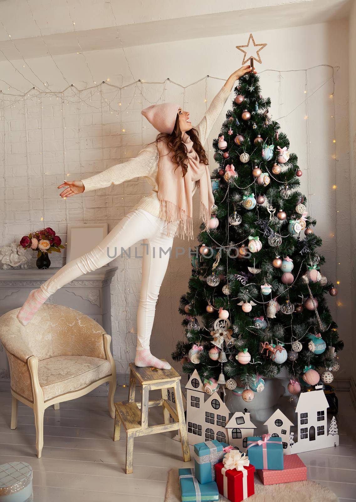 Happy young woman decorates the Christmas tree. A girl in a swea by ViShark