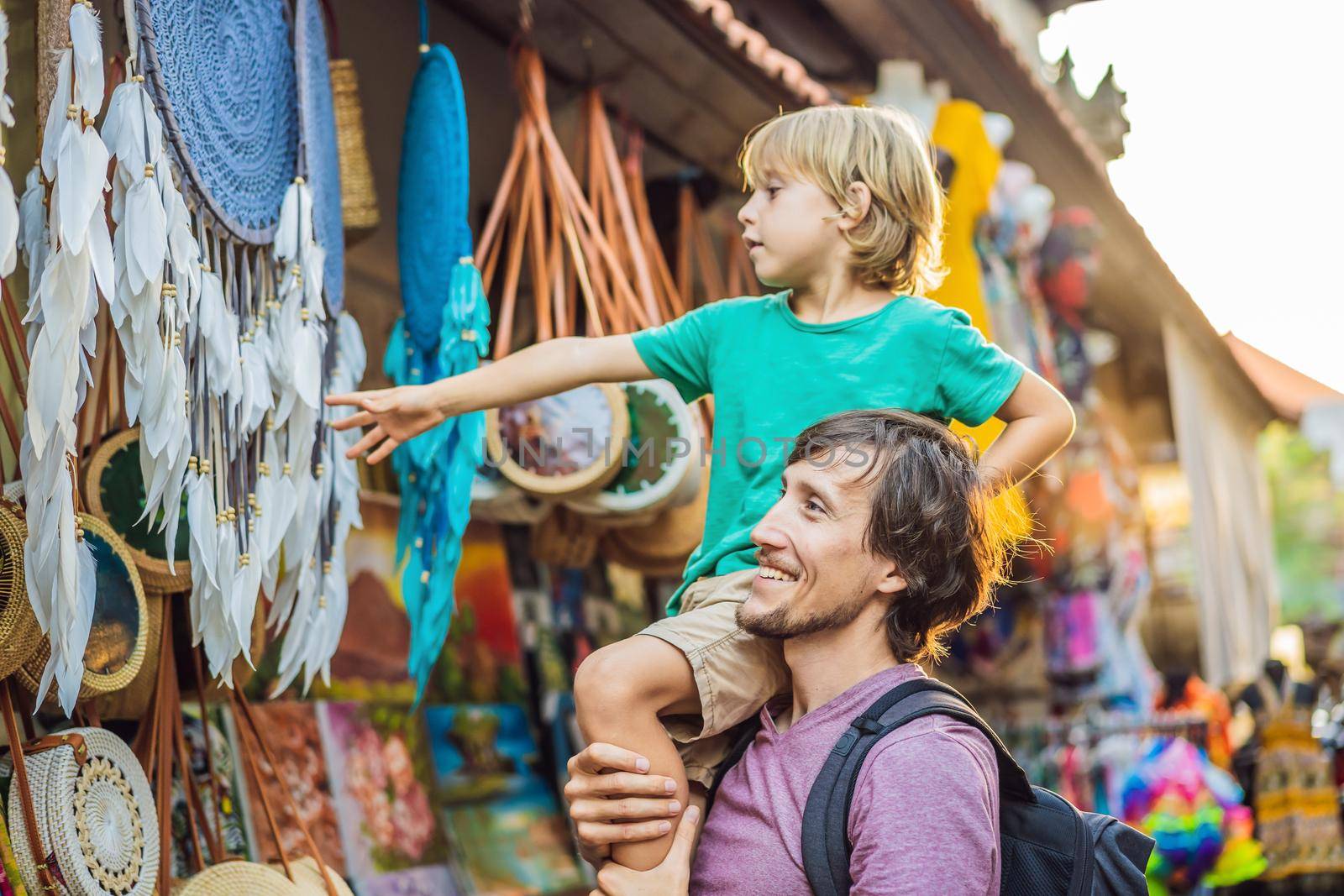 Dad and son at a market in Ubud, Bali. Typical souvenir shop selling souvenirs and handicrafts of Bali at the famous Ubud Market, Indonesia. Balinese market. Souvenirs of wood and crafts of local.