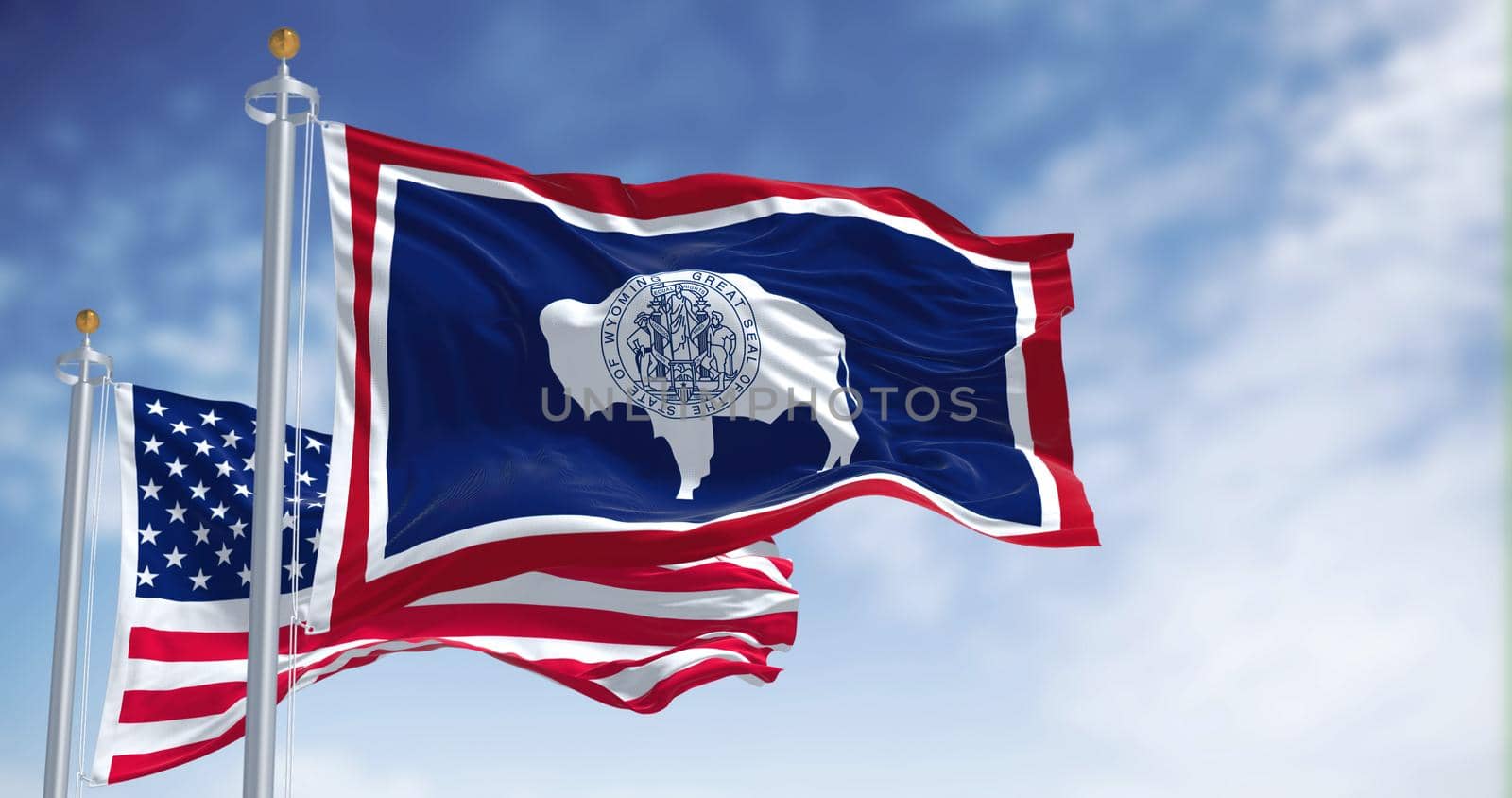 The Wyoming state flag waving along with the national flag of the United States of America. Wyoming is a state in the Mountain West subregion of the Western United States