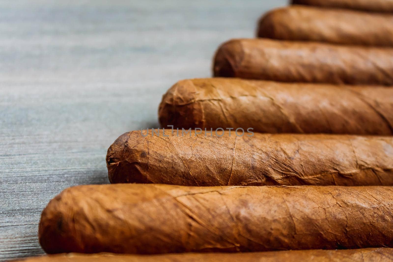 Many cigars on the wooden background. Rolled cigars by JuliaDorian