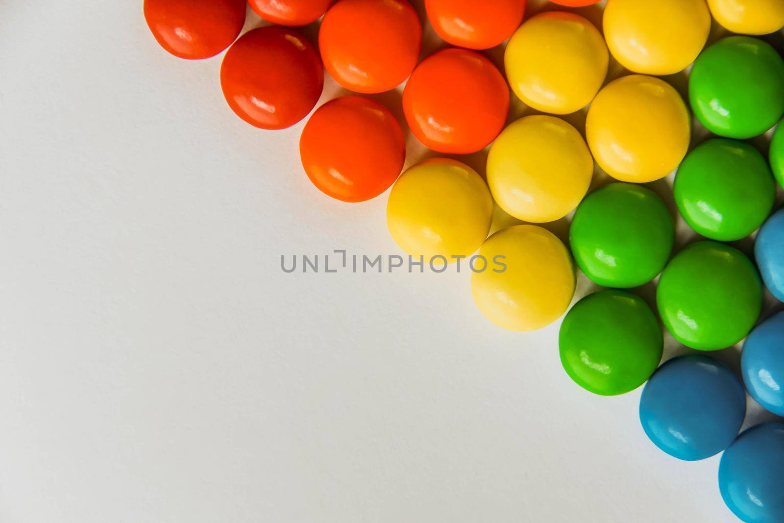 Rainbow of multicolored sweet candy dragees on isolated white background. Decorative Creative composition of round candy dragees in Rainbow colors. Concept Summer. Top view. Flat lay.