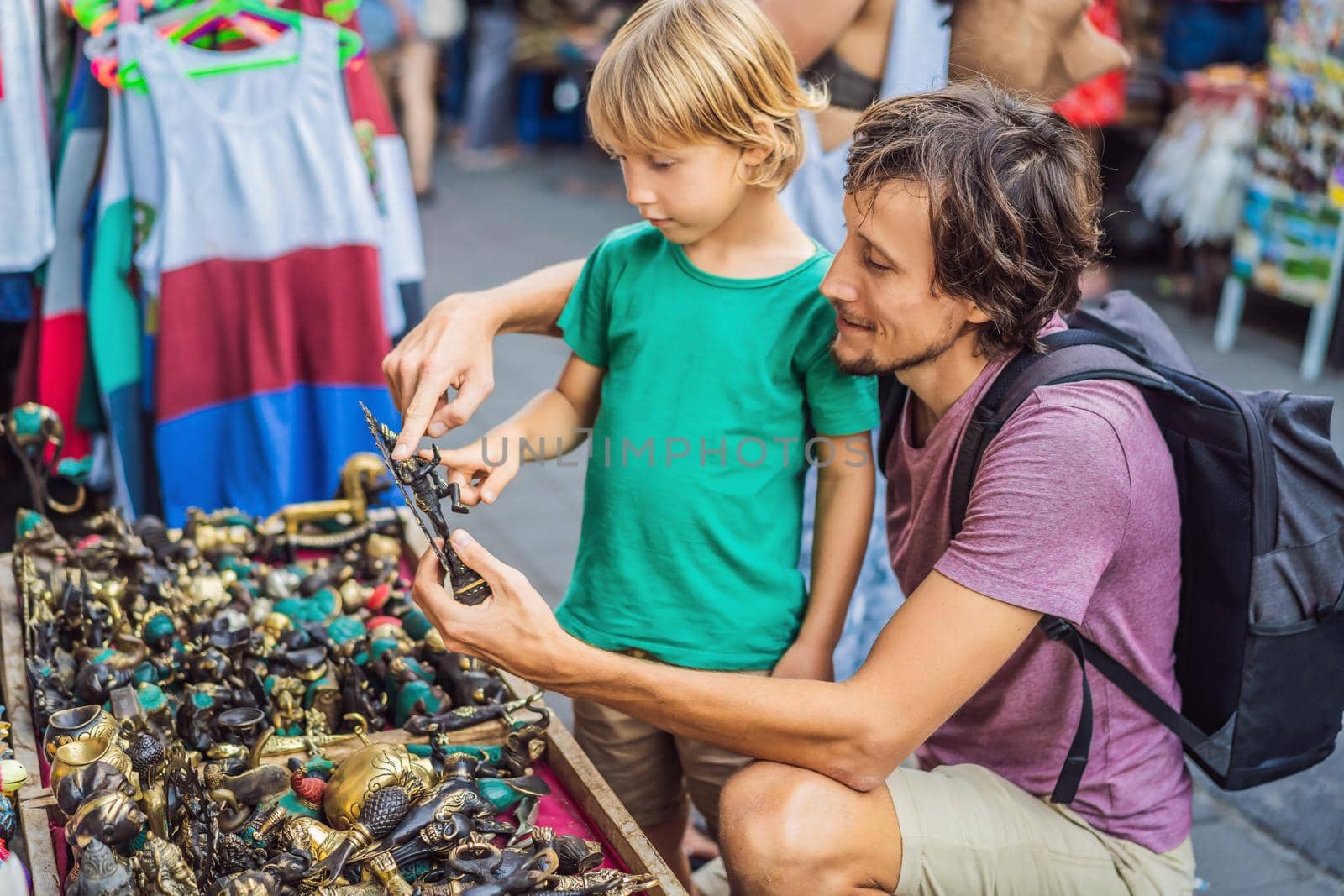 Dad and son at a market in Ubud, Bali. Typical souvenir shop selling souvenirs and handicrafts of Bali at the famous Ubud Market, Indonesia. Balinese market. Souvenirs of wood and crafts of local.