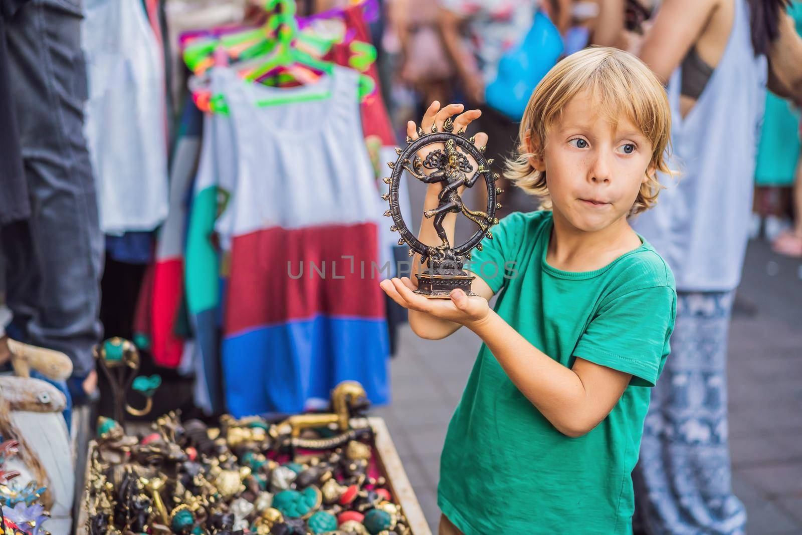 Boy at a market in Ubud, Bali. Typical souvenir shop selling souvenirs and handicrafts of Bali at the famous Ubud Market, Indonesia. Balinese market. Souvenirs of wood and crafts of local residents by galitskaya