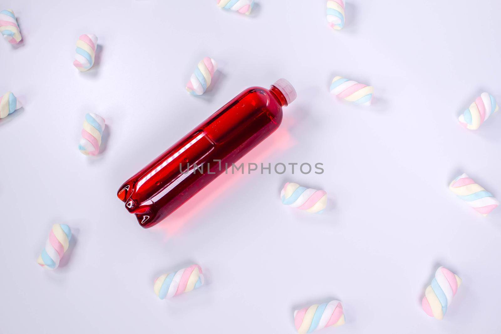 Bottle of red smoothie on white background with twisted marshmallows. Top view. Sweet drink. Detox summer drink. Healthy fresh juice bottle. Vegan and vegetarian concept. by JuliaDorian