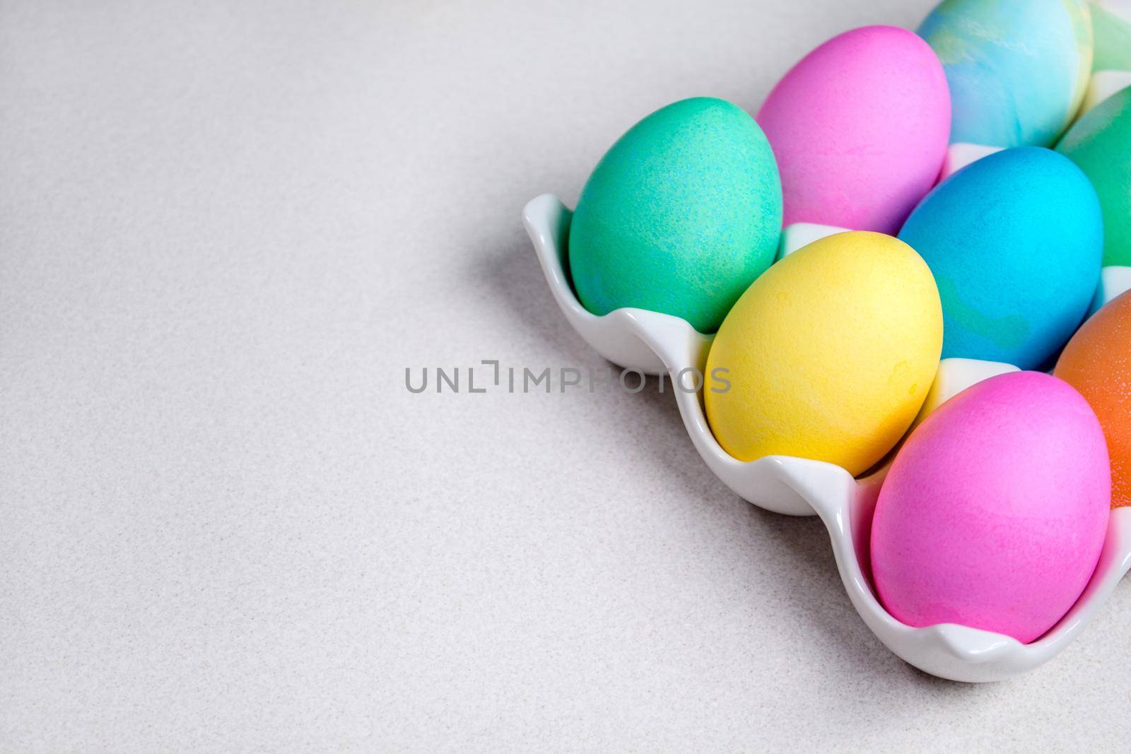 Bright colorful painted Easter eggs lying on white table. Traditional decoration by JuliaDorian
