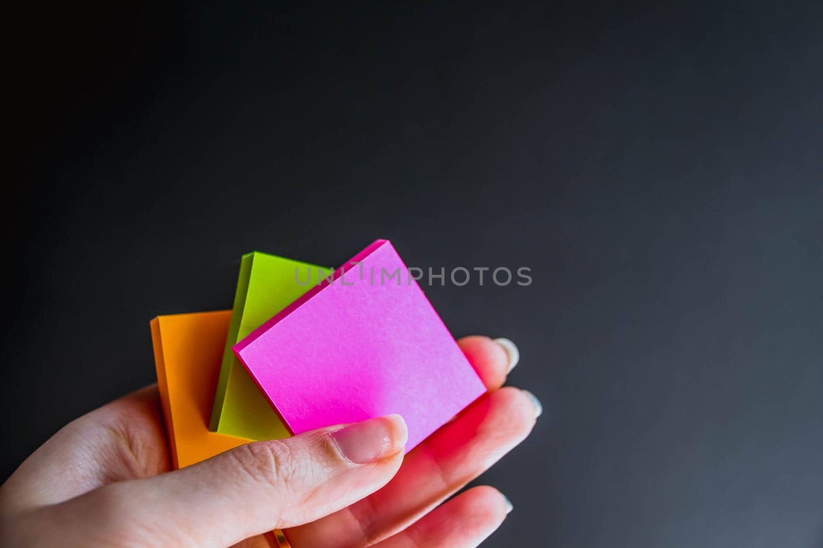 Hand with colorful pink, green, orange notes on black background by JuliaDorian