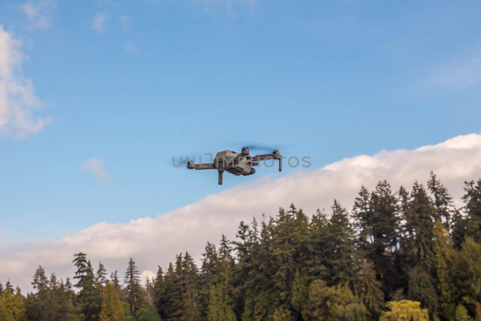 Vancouver, BC Canada - September 2, 2020: Small drone flying over the green forest in suburban area by JuliaDorian