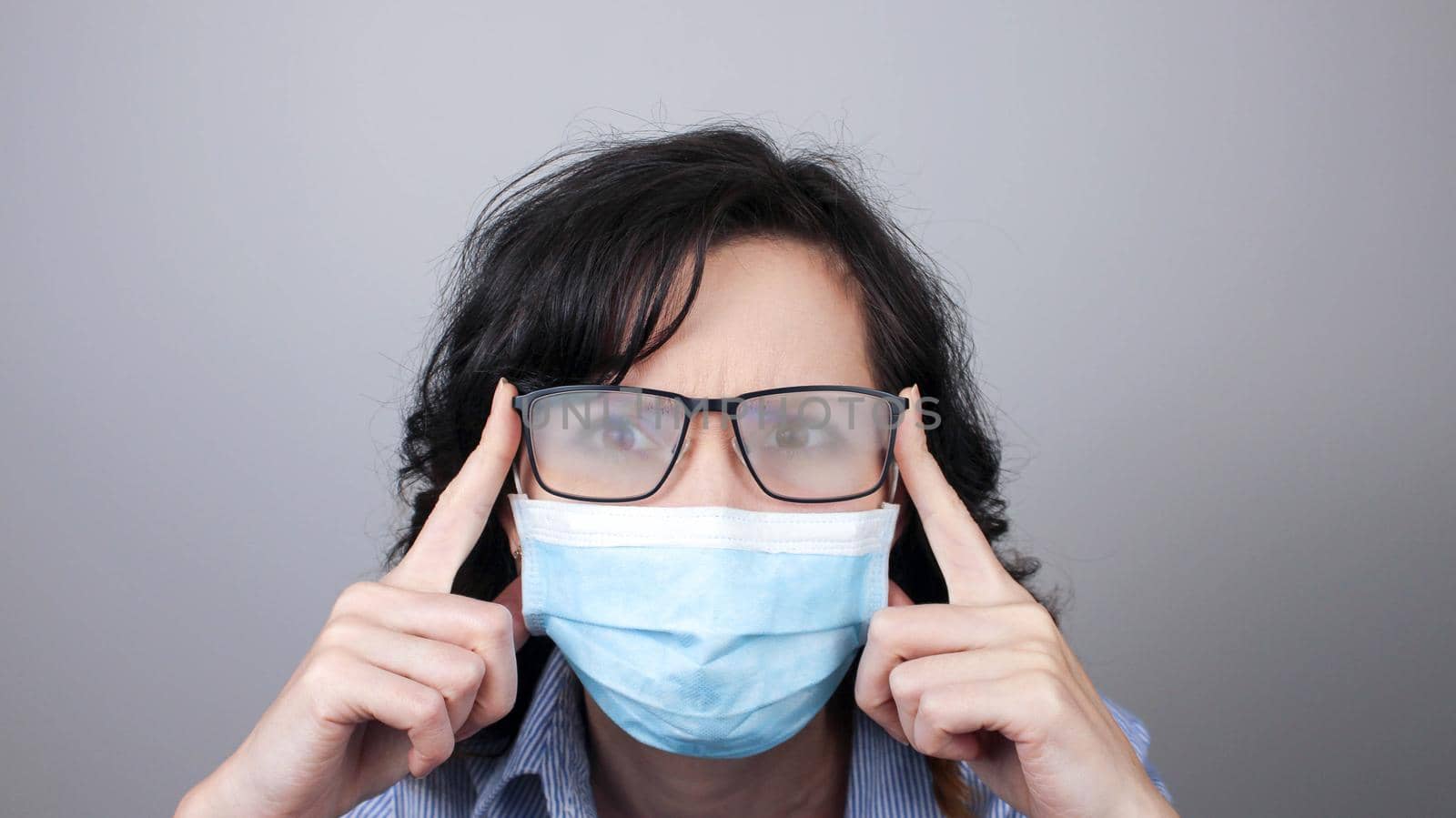 Woman wearing protection face mask against coronavirus and misted glasses. Woman in a mask looking in a mirror. Medical mask, Close up shot, Select focus, Prevention from covid19