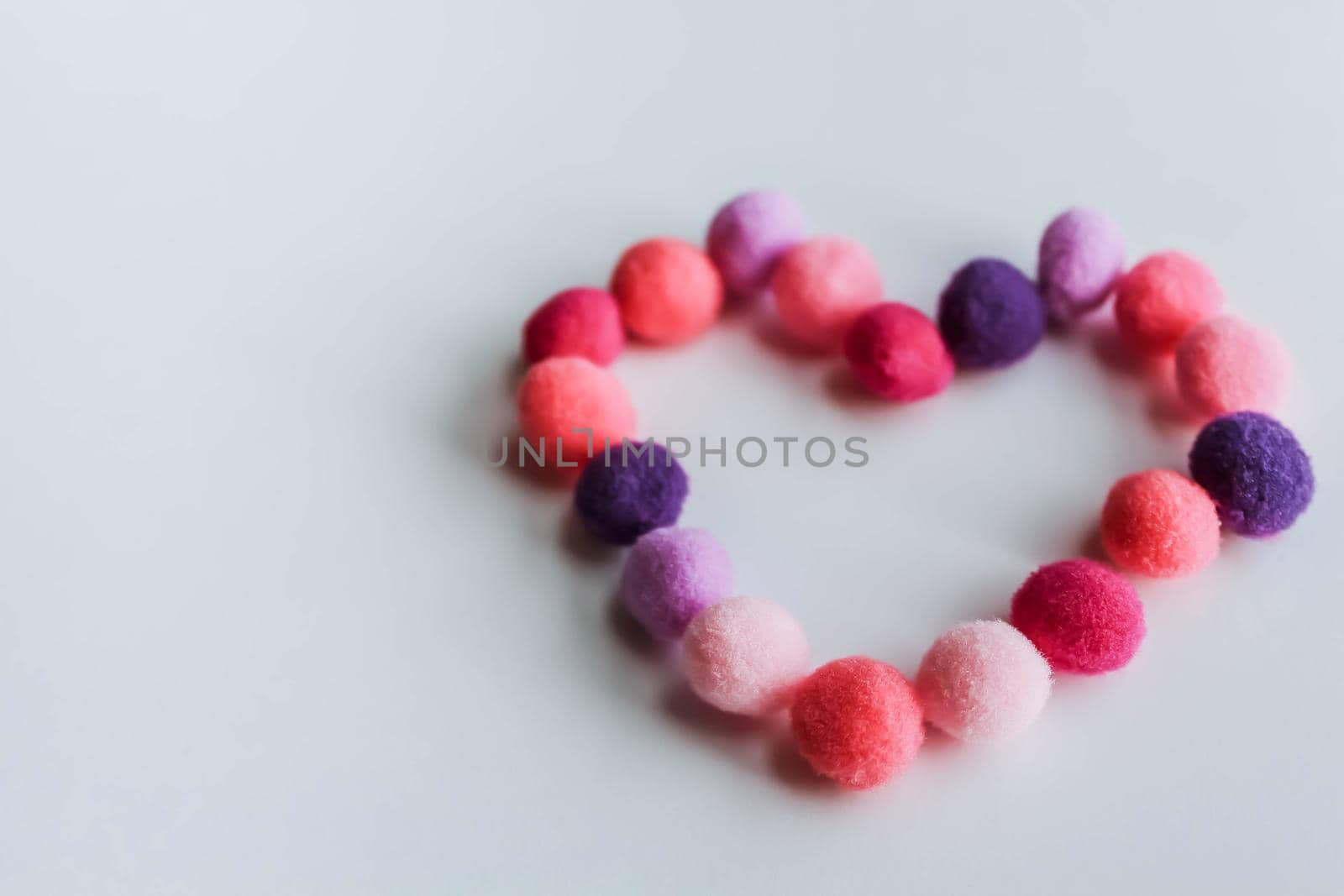 A beautiful, gentle heart made of soft pom-poms against a light background. Heart love, love background, place for text by JuliaDorian