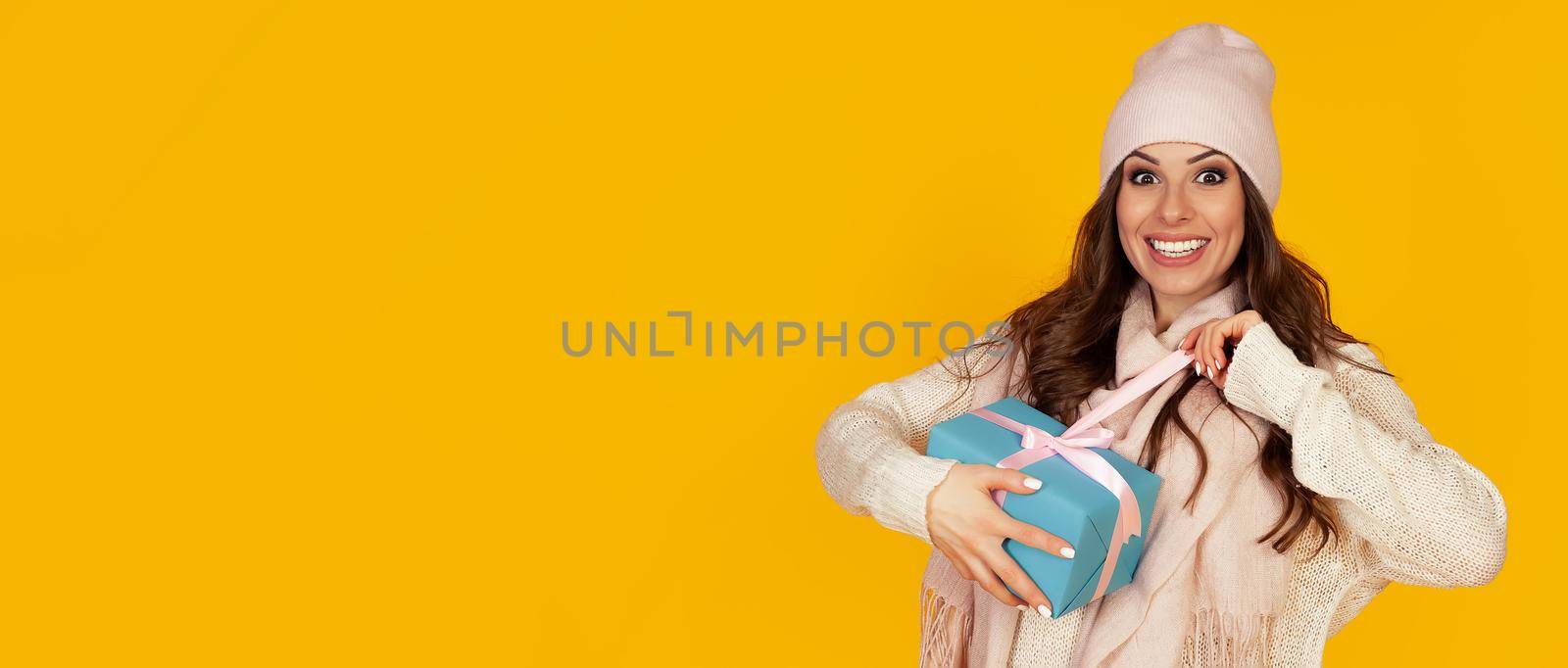 Happy young woman with open mouth opening a gift box of Christmas present, Girl looks into the gift box and laughs with happiness. The concept of gifts and surprises for the new year and christmas
