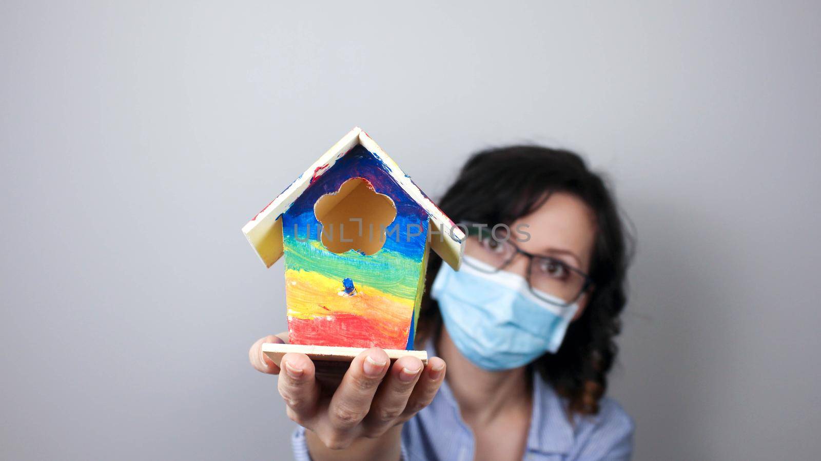 Woman wearing protection face mask against coronavirus and glasses. Woman in a mask showing rainbow house. We will be okay. Medical mask, Close up shot, Select focus, Prevention from covid19
