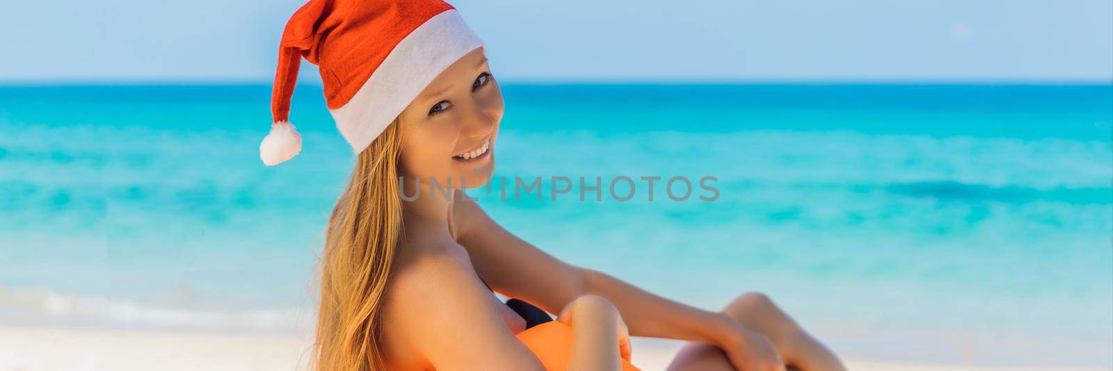 Woman on an inflatable beach couch and Christmas hat on the beach under an umbrella BANNER, LONG FORMAT by galitskaya