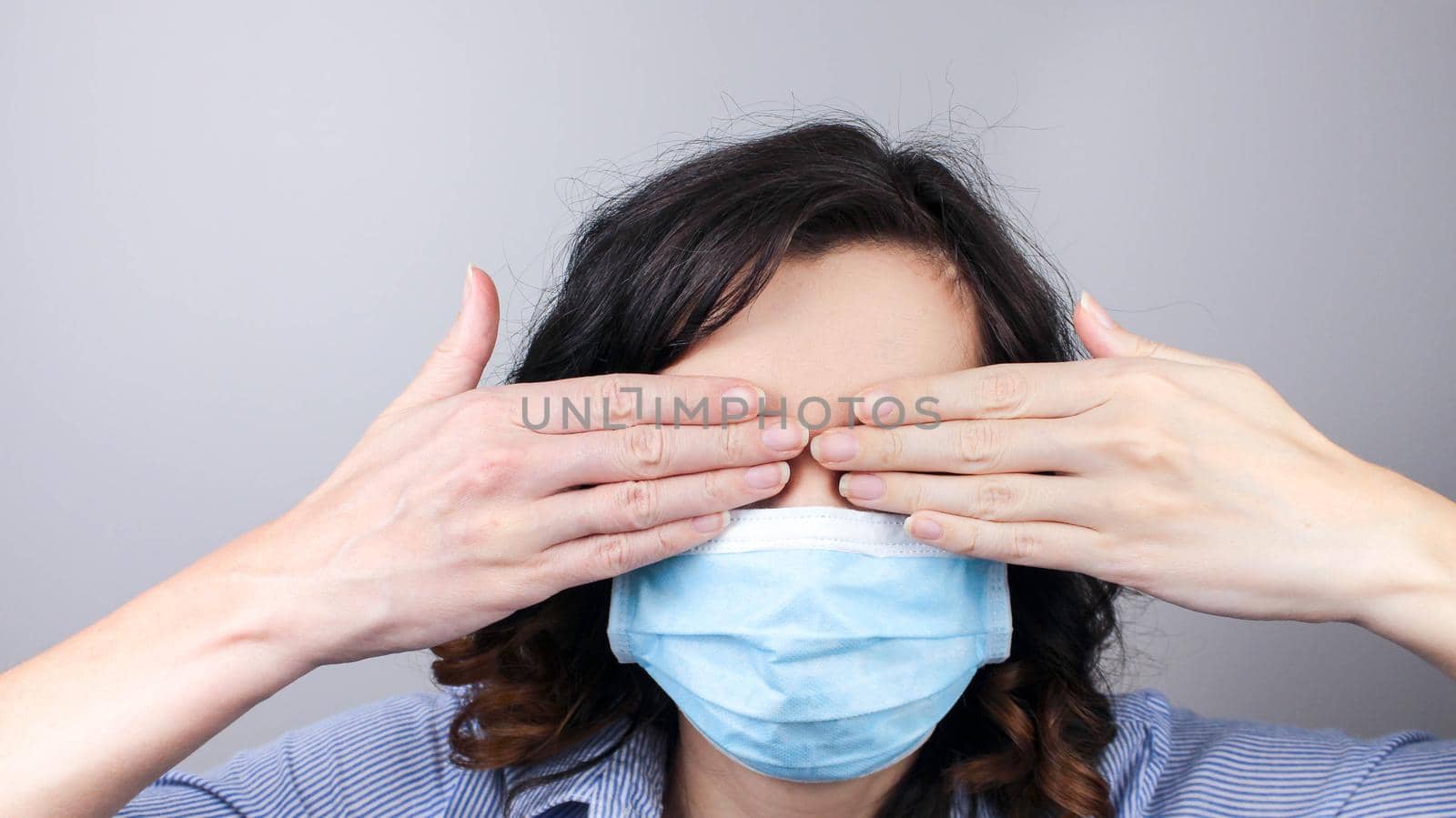 Woman wearing protection face mask against coronavirus covering her eyes with hands. Woman in a mask hiding her eyes. Medical mask, Close up shot, Select focus,