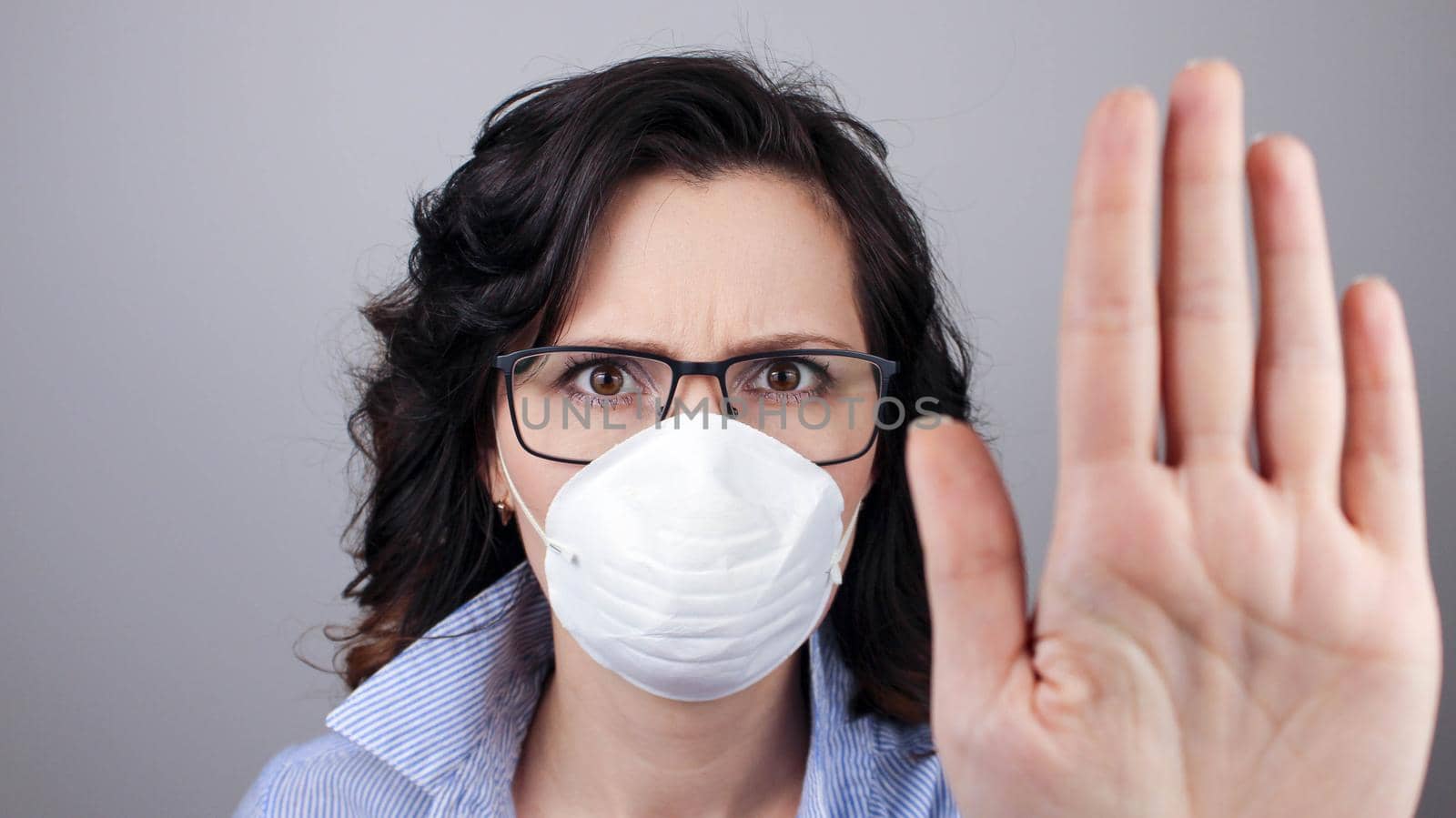 On background woman in mask focus on stretched hand. Keep distance avoid communication, healthcare concept. Woman wearing protection face mask against coronavirus and glasses. Selective focus.