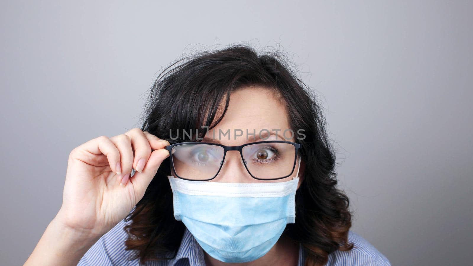 Young woman with foggy glasses caused by wearing disposable mask. Protective measure during coronavirus pandemic by JuliaDorian